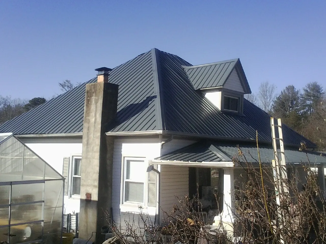 Dark blue standing seam metal roof on a white farmhouse with dormer — Slate & Tile Roof Repair by Roofing Brothers in Fountain City