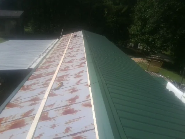 Old rusted panels beside newly installed green metal roofing — Wind Damage Roof Repair by Roofing Brothers in Fountain City