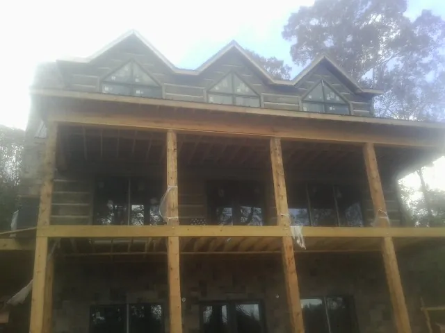 Dormers and porch framing on a large log home under construction — Roof Coating work by our crew in Fountain City