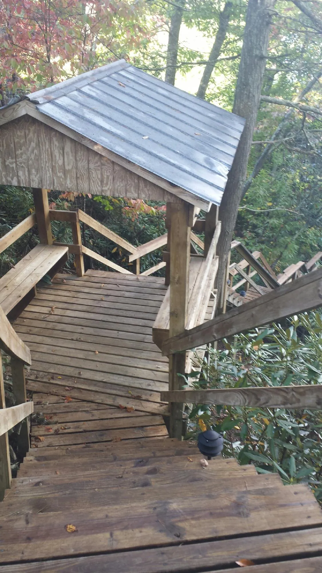 Metal roofed shelter over wooden steps on a wooded walkway — Skylight Repair & Installation work by our crew in Fountain City