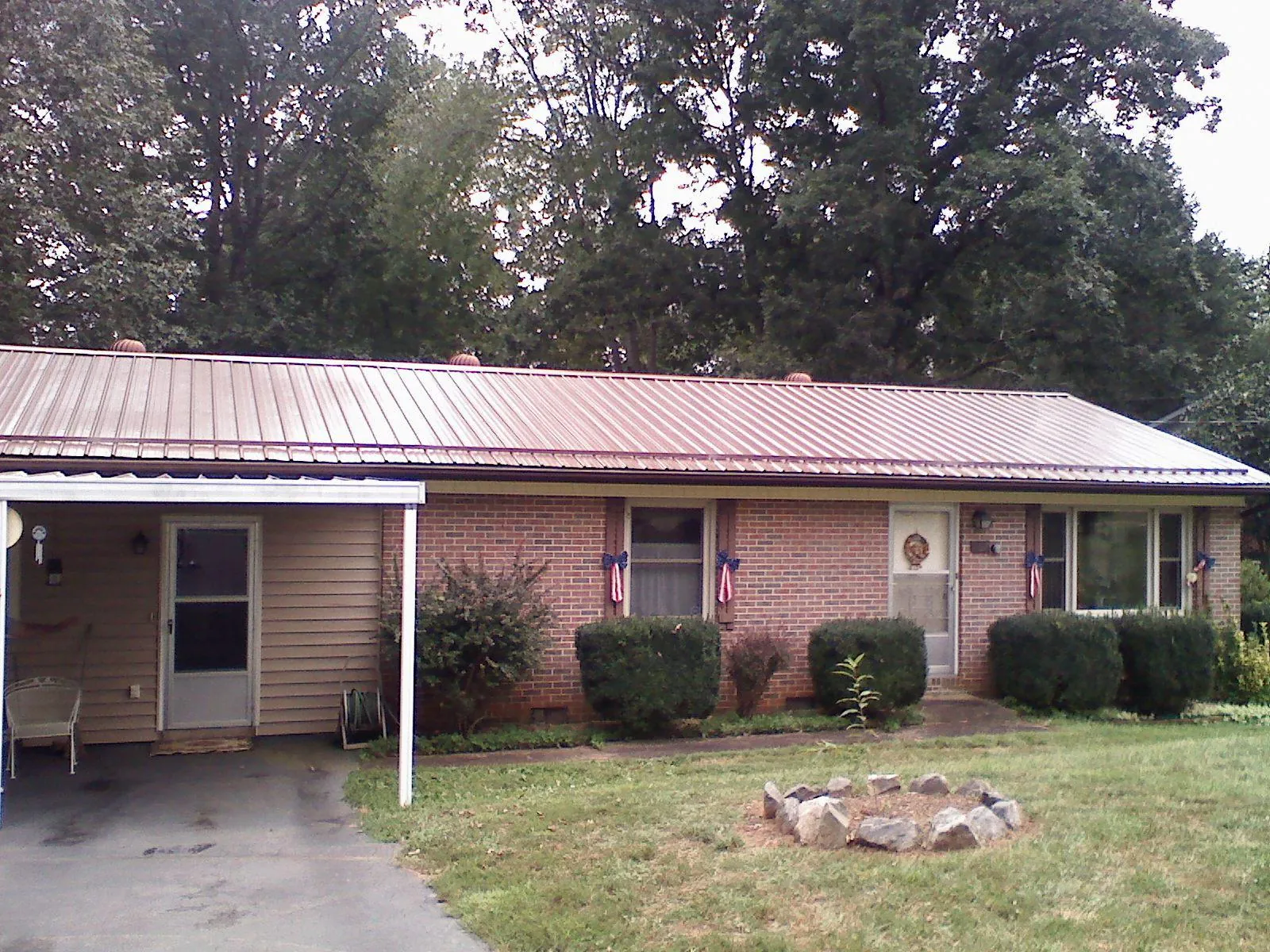 Bronze metal roof and carport on a brick ranch home — Roof Repair work by our crew in Fountain City
