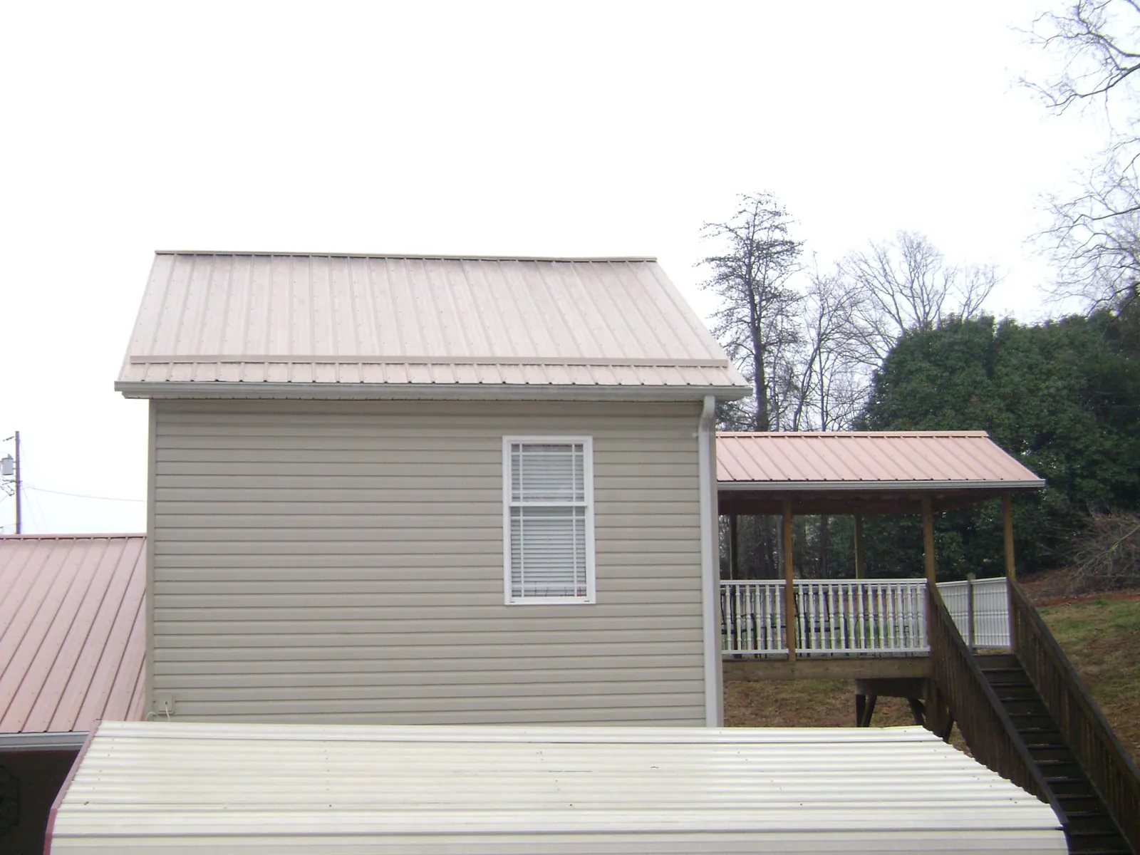 Tan metal roofs on a two story addition and attached porch, from a Roof Replacement job in Fountain City
