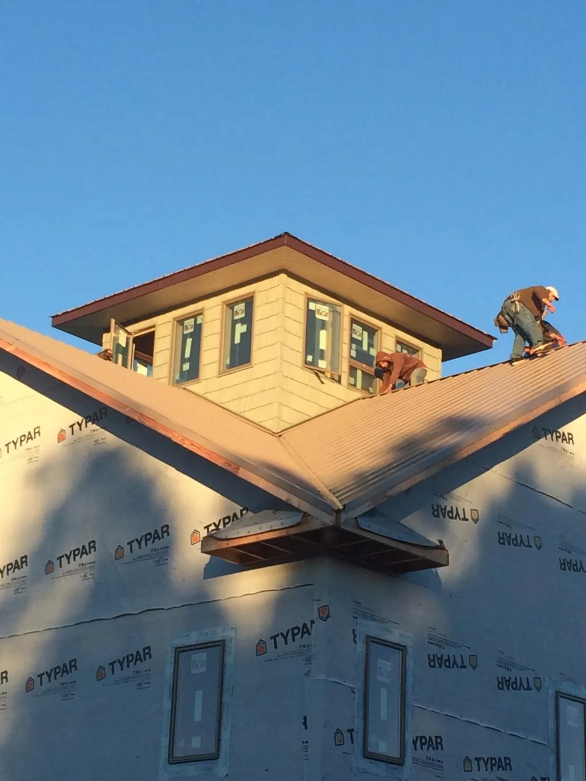 Roofers working around a rooftop cupola on a new metal roof at sunset — Roof Waterproofing in Fountain City by Roofing Brothers